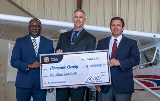 Governor , Superintendent and PHSC President holding large check