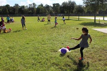 Children playing kick ball on a grassy field